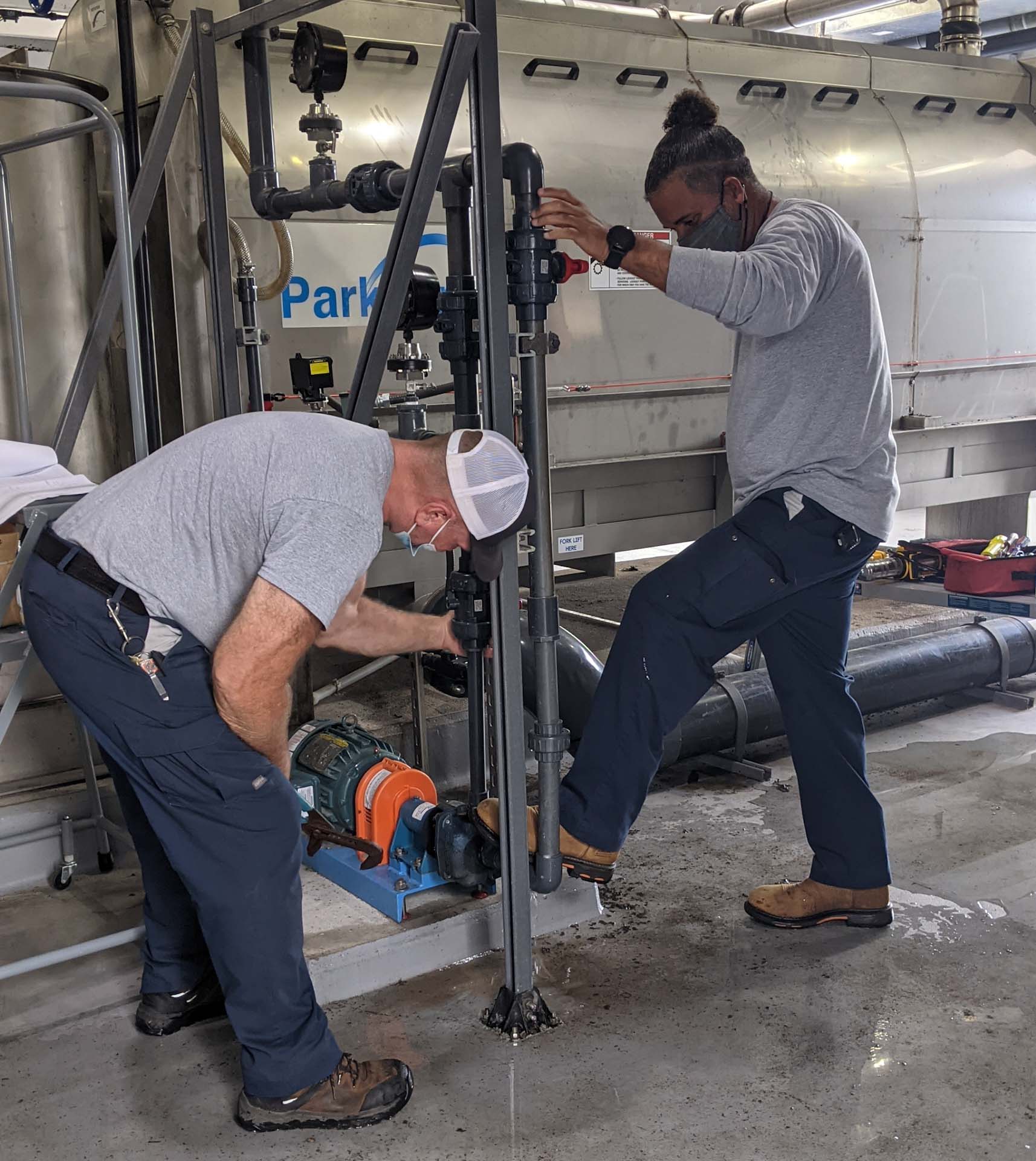 Rod Dail and Marcus Hill repair a pump